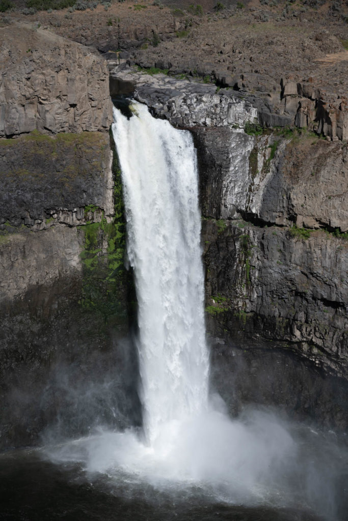 Palouse Falls, cascading down rock cliffs to a pool of water below. 