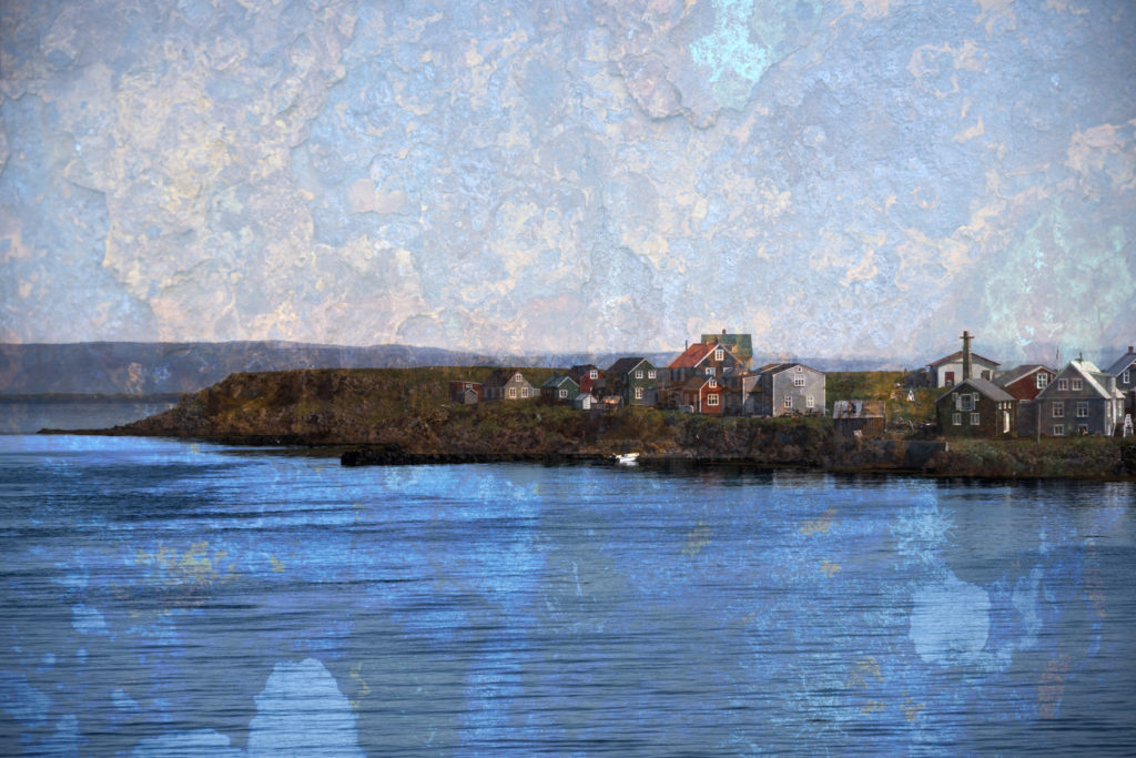 A row of houses in Iceland on a narrow strip of land, with water in front of it, and a distant hill line behind it. 